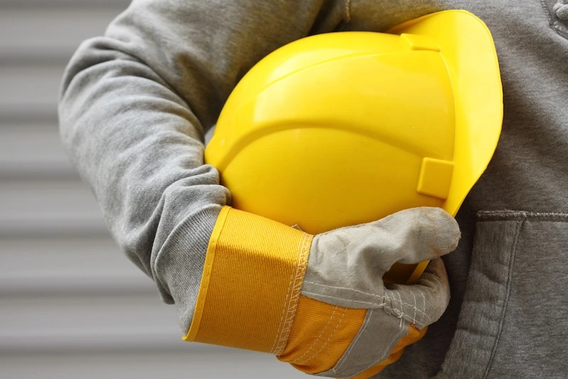 Hand holding yellow hard hat